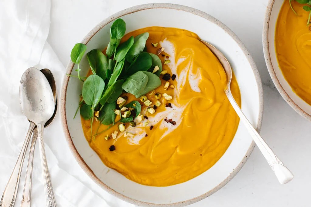 Sweet potato soup in a white bowl with a spoon.